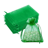 Green sheer organza drawstring gift bags, with a stack of empty bags and one filled with white pearl-like beads on a plain white background.