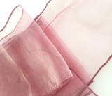 A close-up of a dusty pink sheer organza fabric with thin matching pink ties, draped diagonally against a white background.