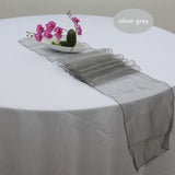 A silver grey organza table runner laid out on a white table, with a floral arrangement at the top and a tag that reads 'Silver Grey'.