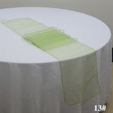 A green organza table runner on a white round tablecloth.